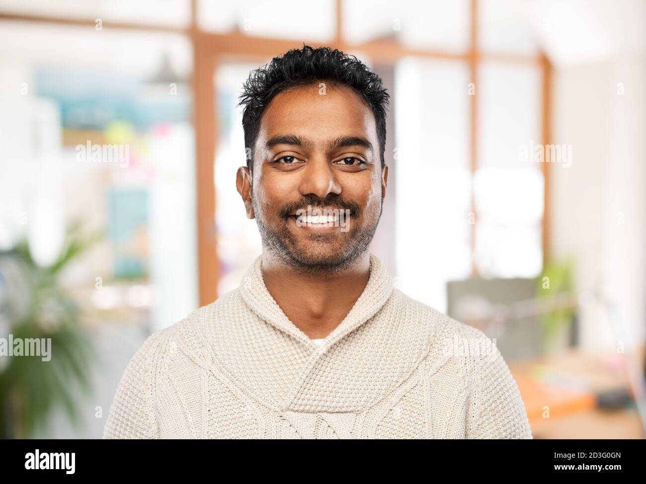 indiano uomo in maglione su sfondo ufficio Foto Stock