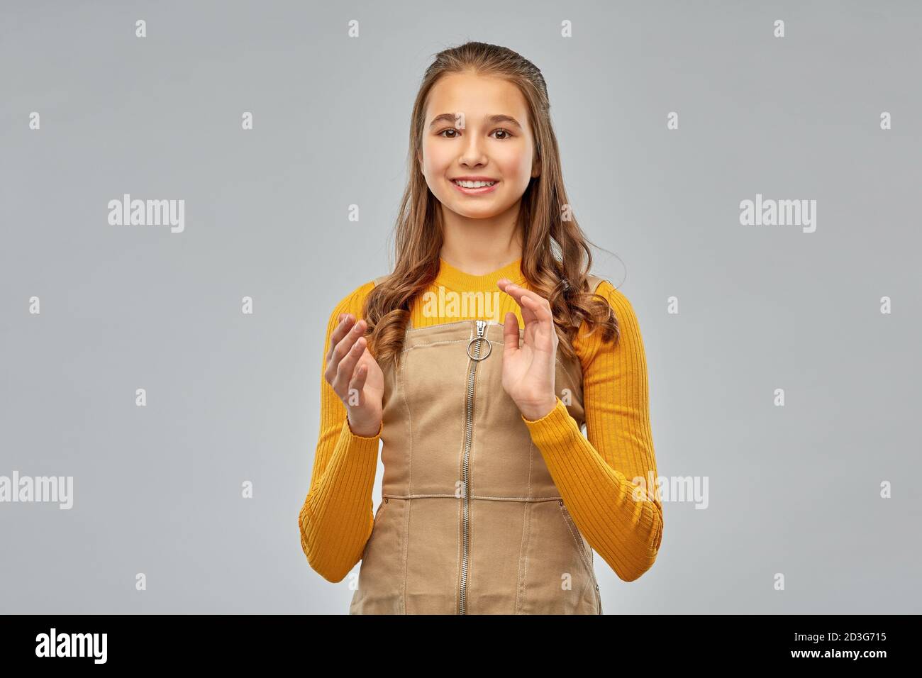 sorridente ragazza adolescente applaudendo su sfondo grigio Foto Stock