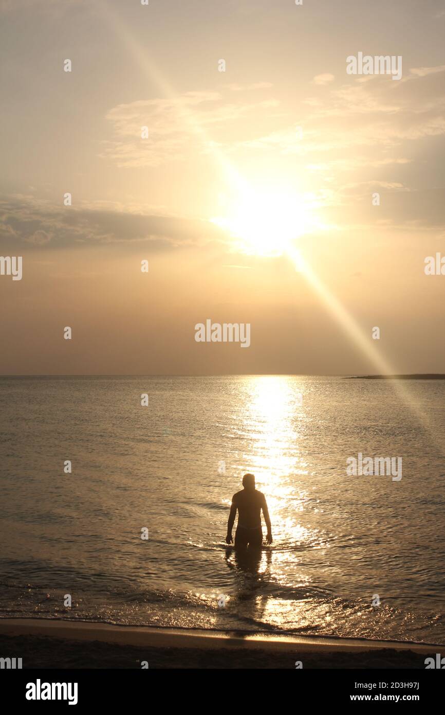 Un uomo gioca al Tramonto a Panagia Beach nell'isola di Elafonisos, nella parte meridionale del Peloponneso, in Grecia Foto Stock