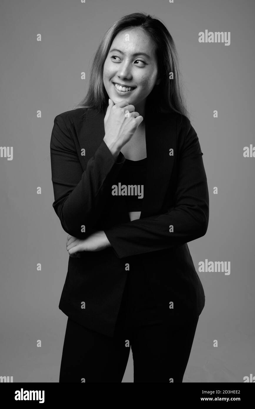 Ritratto di felice giovane donna d'affari asiatica su sfondo grigio Foto Stock