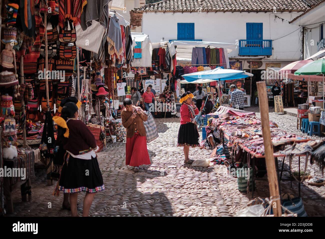Stallholders che vendono souvenir e vestiti al mercato di Pisaq con i turisti sullo sfondo Foto Stock