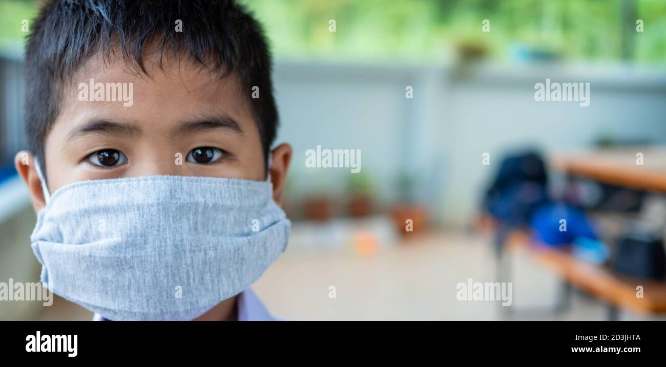 Primo piano ritratto di un ragazzo carino che indossa una maschera protettiva e sta guardando la fotocamera. Foto Stock
