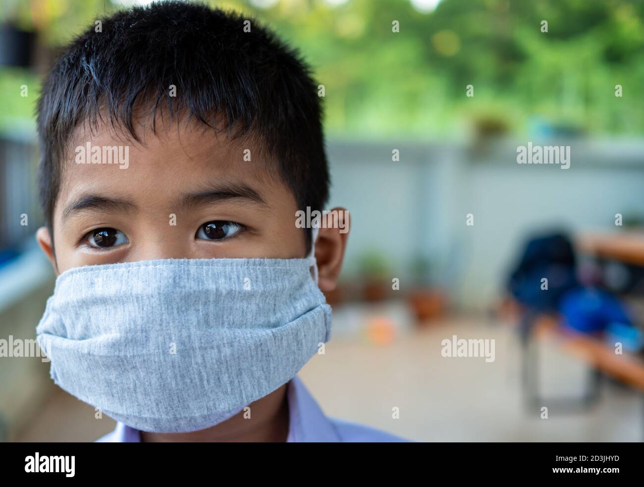 Primo piano di un ragazzo carino che indossa una maschera protettiva e sta guardando qualcosa. Foto Stock