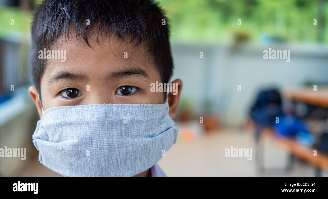 Primo piano ritratto di un ragazzo carino che indossa una maschera protettiva e sta guardando la fotocamera. Foto Stock
