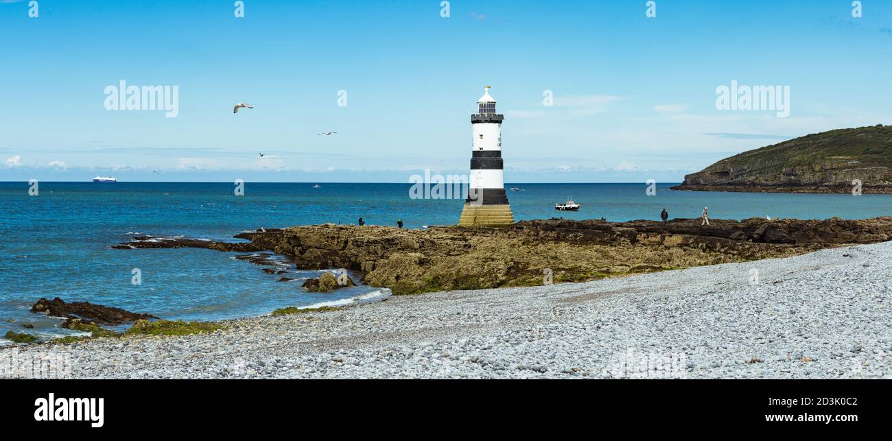 Trwyn Du Lighthouse a Penmon, Anglesey, Galles con il traghetto utilizzato per trasportare le ali Airbus in Francia in attesa sulla marea offshore Foto Stock