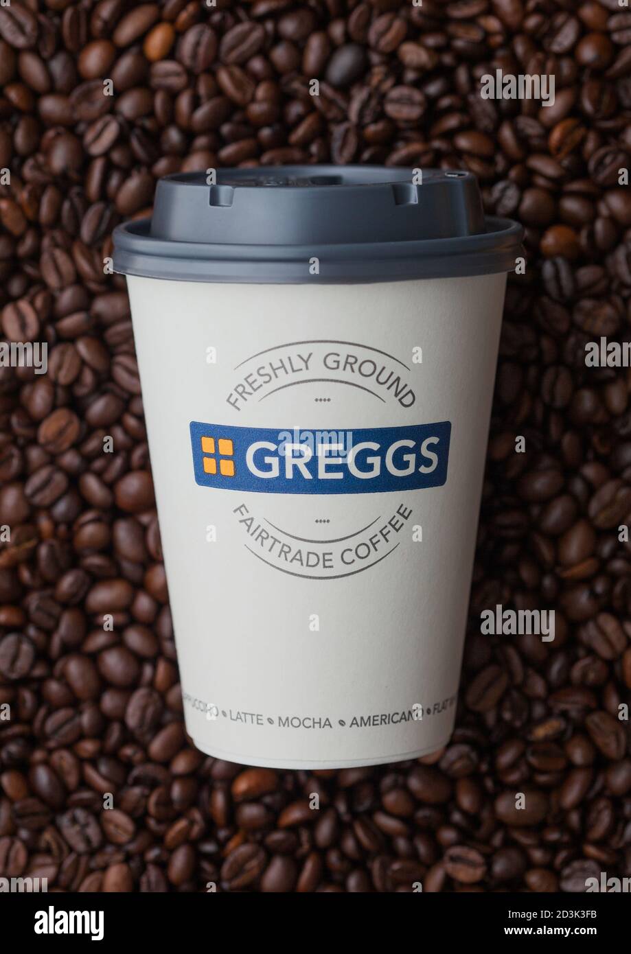 LONDRA, Regno Unito - 09 SETTEMBRE 2020: Tazza di carta di caffè GREGGS appena macinato Fairtrade sopra i chicchi di caffè fresco crudo. Foto Stock