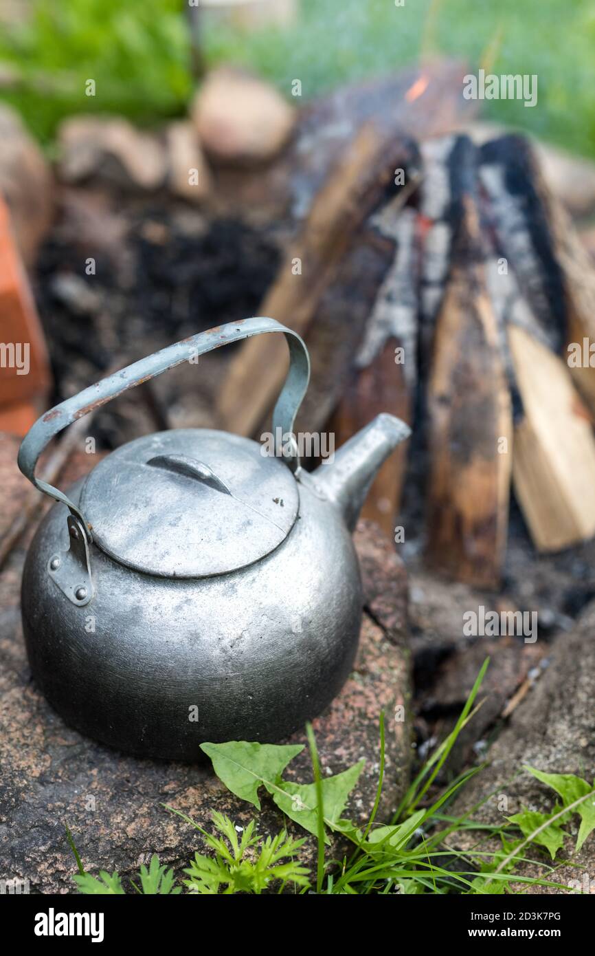 bollitore per picnic all'aperto con un tocco vintage vicino a un falò. Cucina all'aperto, fuoco di cottura. Foto Stock