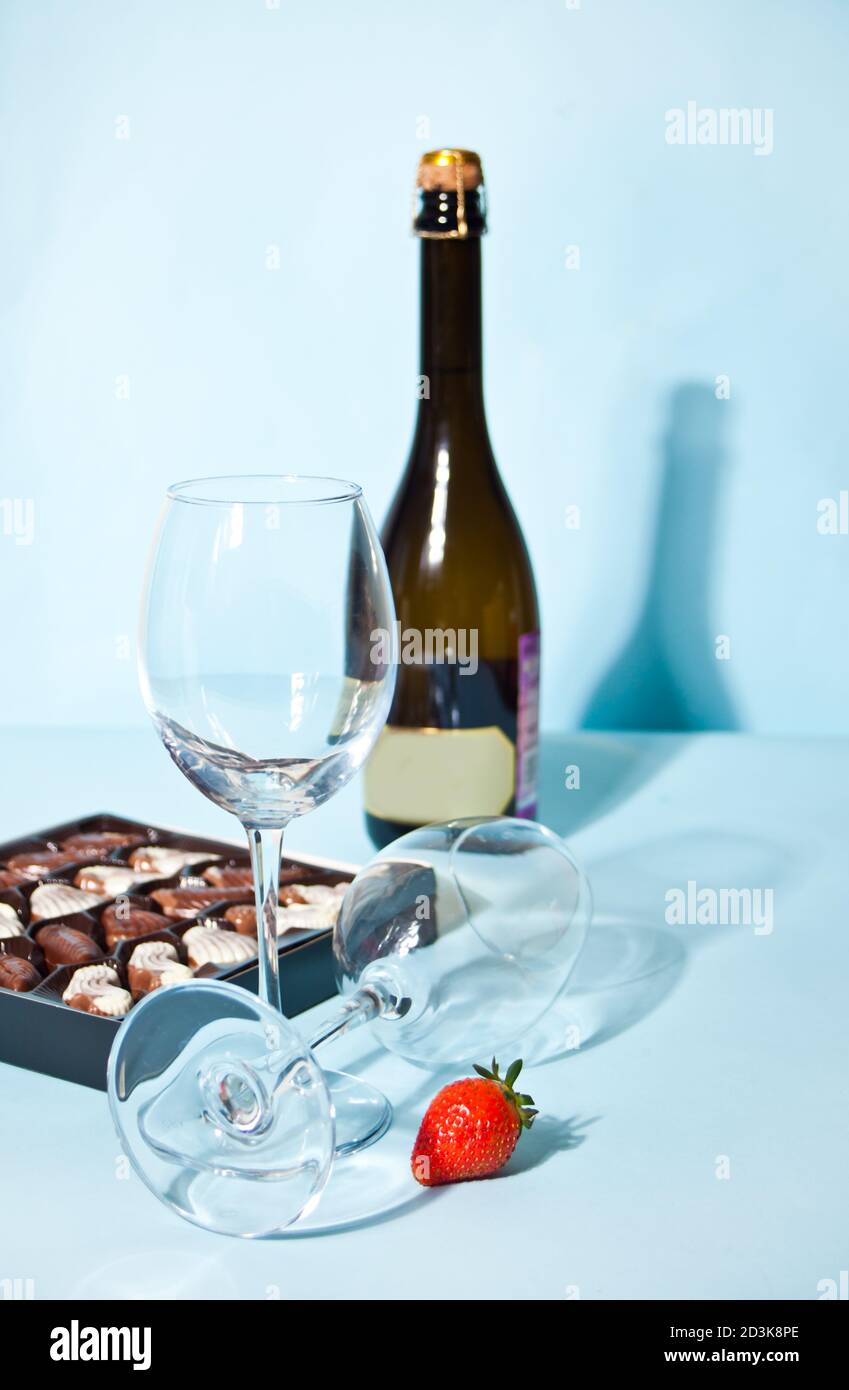 Bicchieri vuoti per champagne o vino. Scatola di cioccolatini e bottiglia sullo sfondo Foto Stock