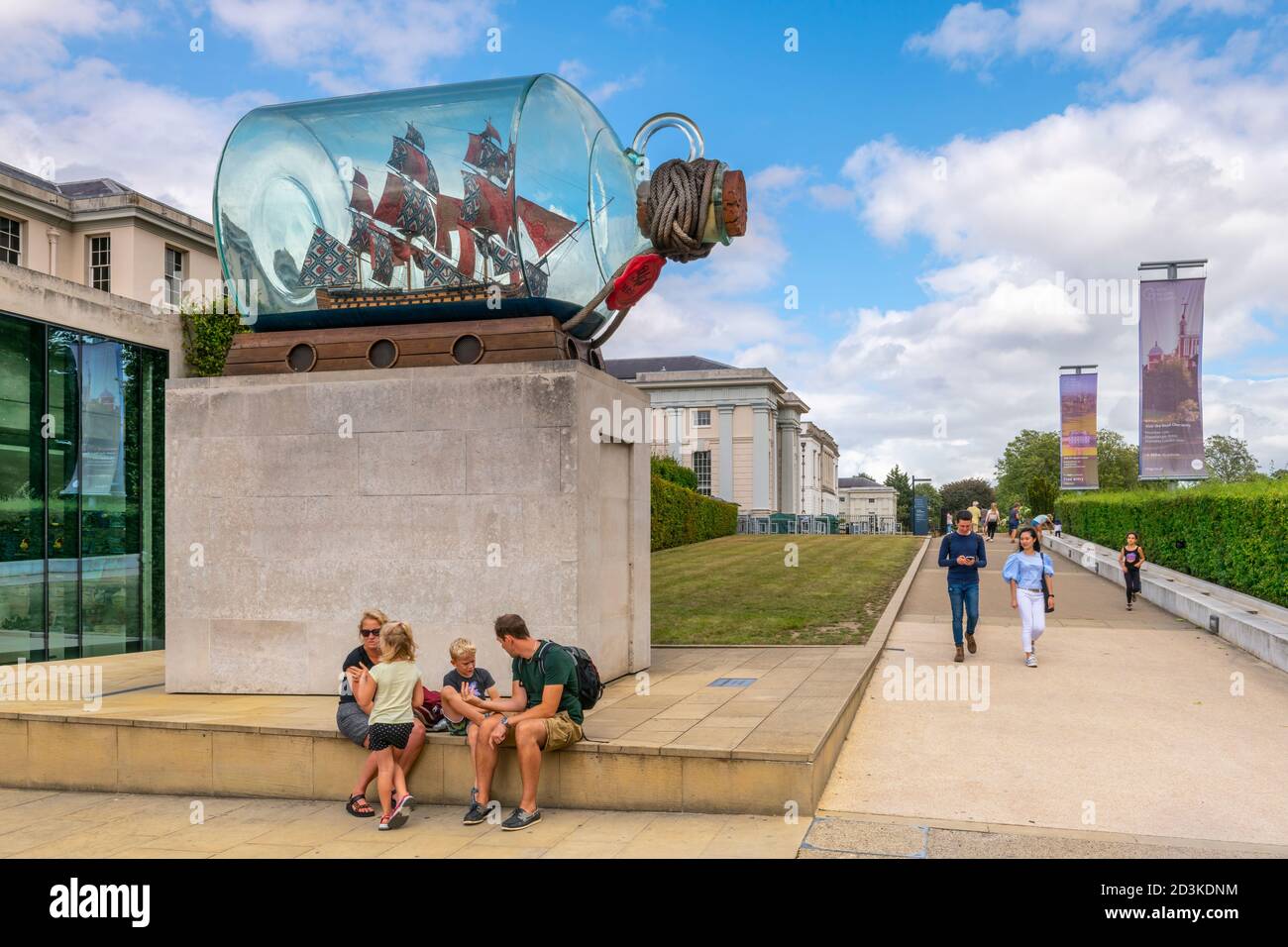 Una famiglia si siede sotto la nave di Lord Nelson in una bottiglia, un'opera d'arte di Yinka Shonimbare, fuori dal National Maritime Museum di Greenwich, Londra. Foto Stock