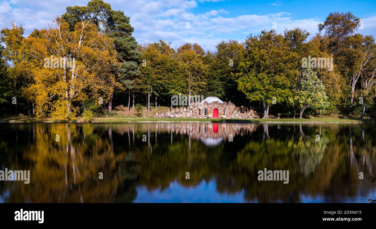 Gosford Estate, East Lothian, Scozia, Regno Unito, 8 ottobre 2020. Regno Unito Meteo: Autunno sole riflessioni. Il bizzarro Lodge arricchiato in pietra arenaria circondato da alberi d'autunno si riflette nel lago artificiale Foto Stock