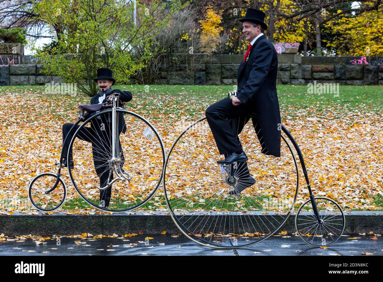 Due ciclisti sui costumi delle biciclette Penny Farthing, indossando un cappotto di coda Foto Stock