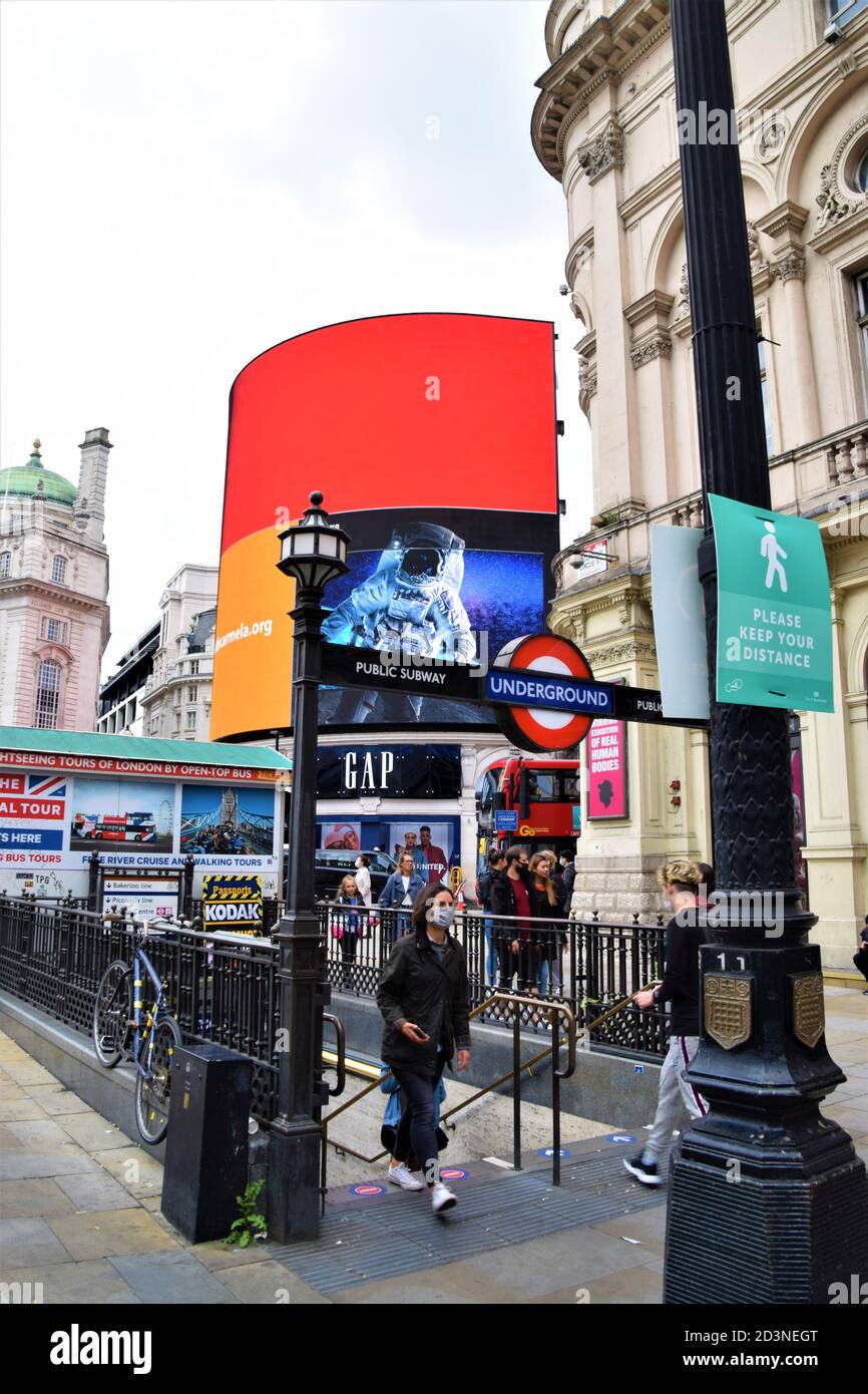 Donna con maschera protettiva esce dalla stazione della metropolitana Piccadilly Circus, Londra, Regno Unito 2020 Foto Stock