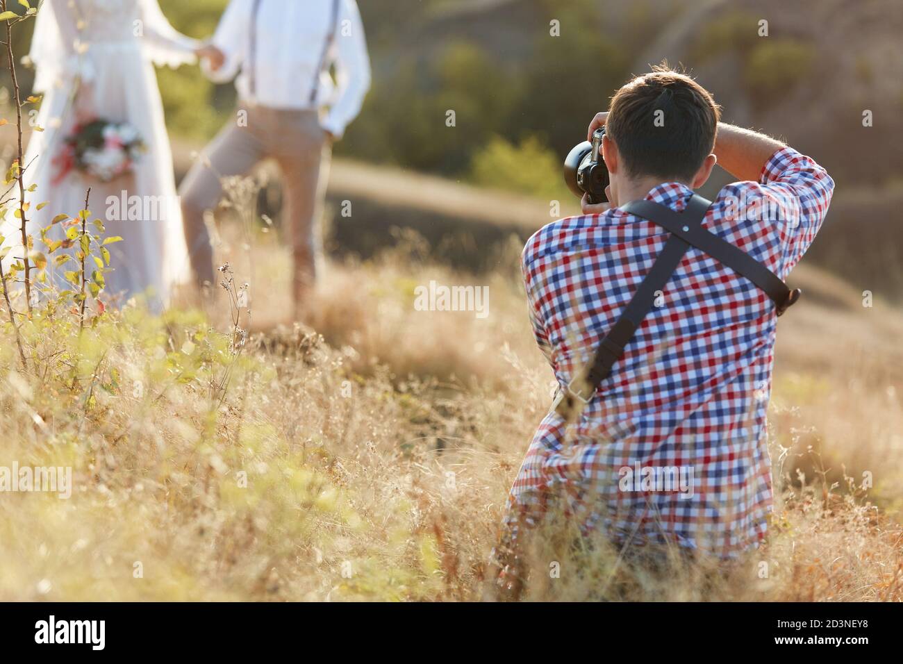 il fotografo professionista del matrimonio scatta foto di coppie di nozze in natura al tramonto, fotografo uomo in azione Foto Stock
