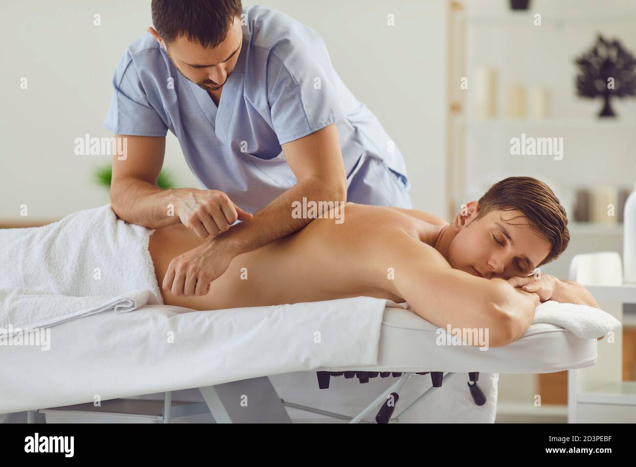 Un giovane rilassato che si gode di un massaggio professionale del corpo nel salone termale o centro di salute Foto Stock