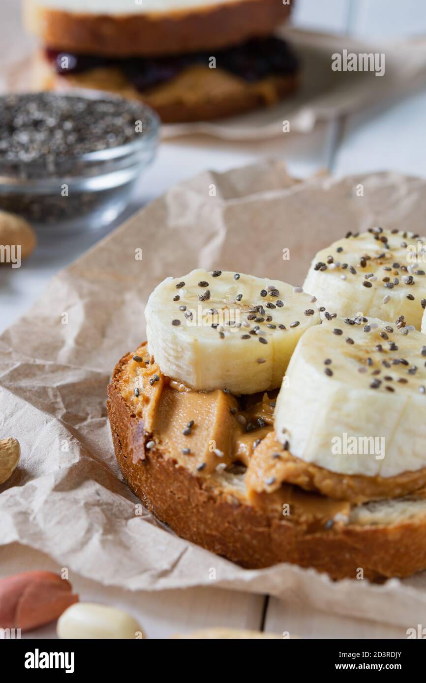 fast food, snack, due panini con marmellata di burro di arachidi e banane su un tavolo di legno bianco Foto Stock