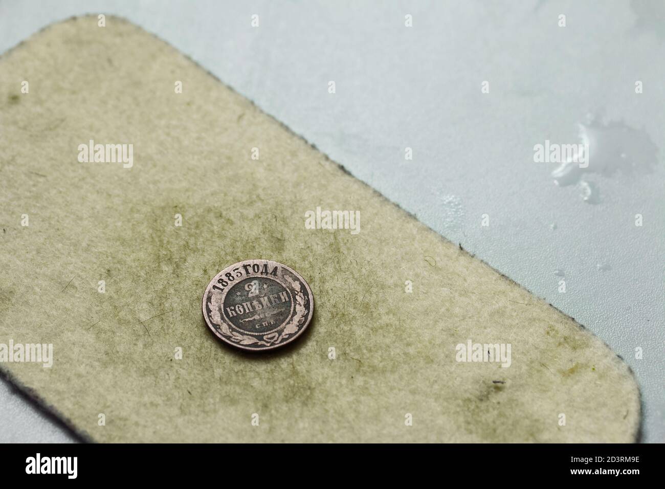 Una moneta di rame patinata con unguento di zolfo giace su un feltro. Foto Stock