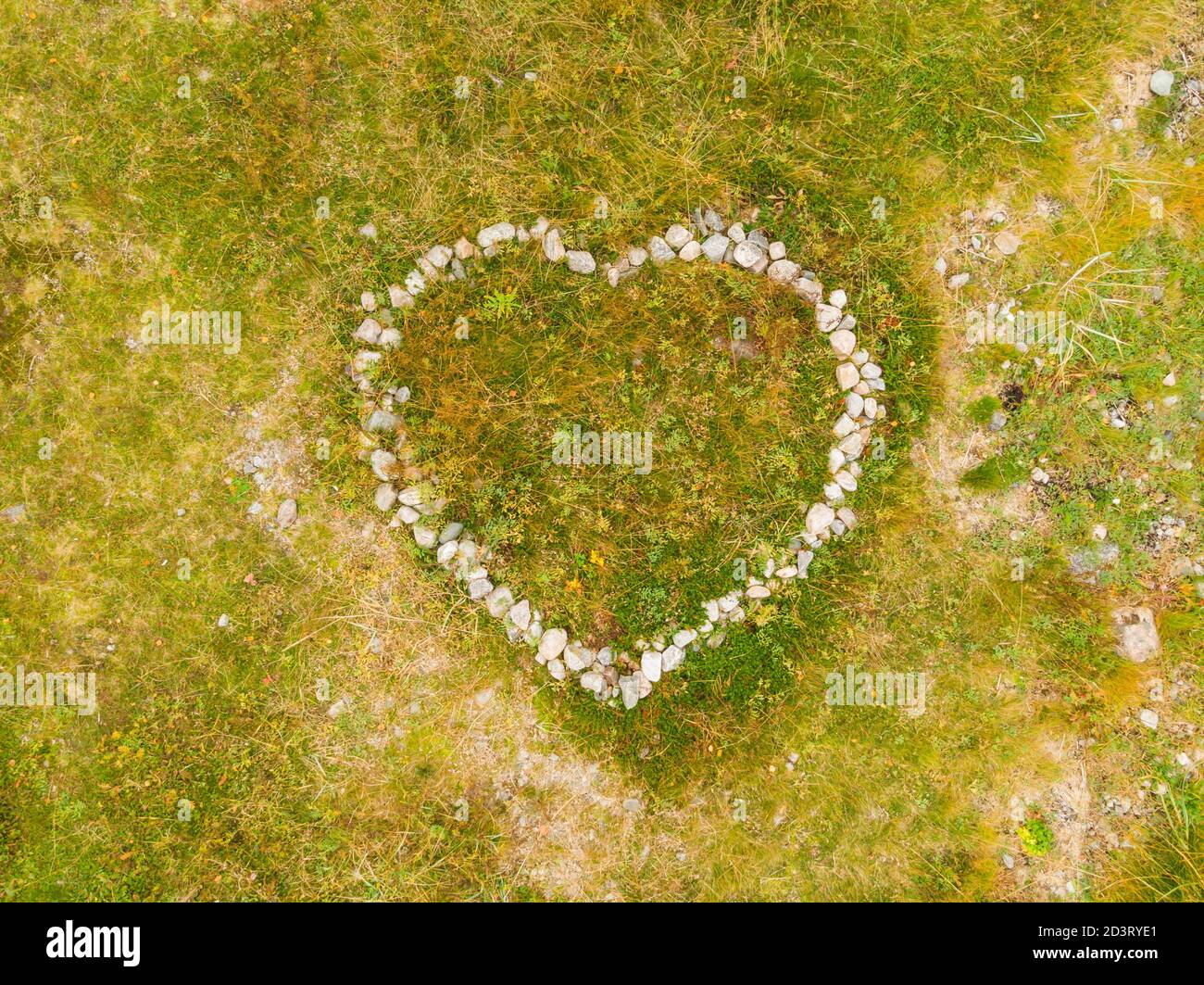 Cuore di pietra. Cuore fatto di pietre su erba verde Foto Stock