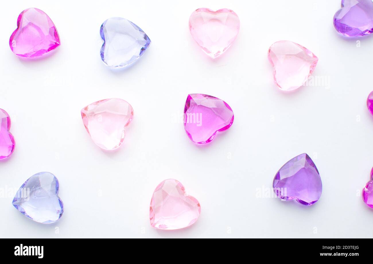 Cristalli di cuori rosa e viola su sfondo bianco Foto Stock