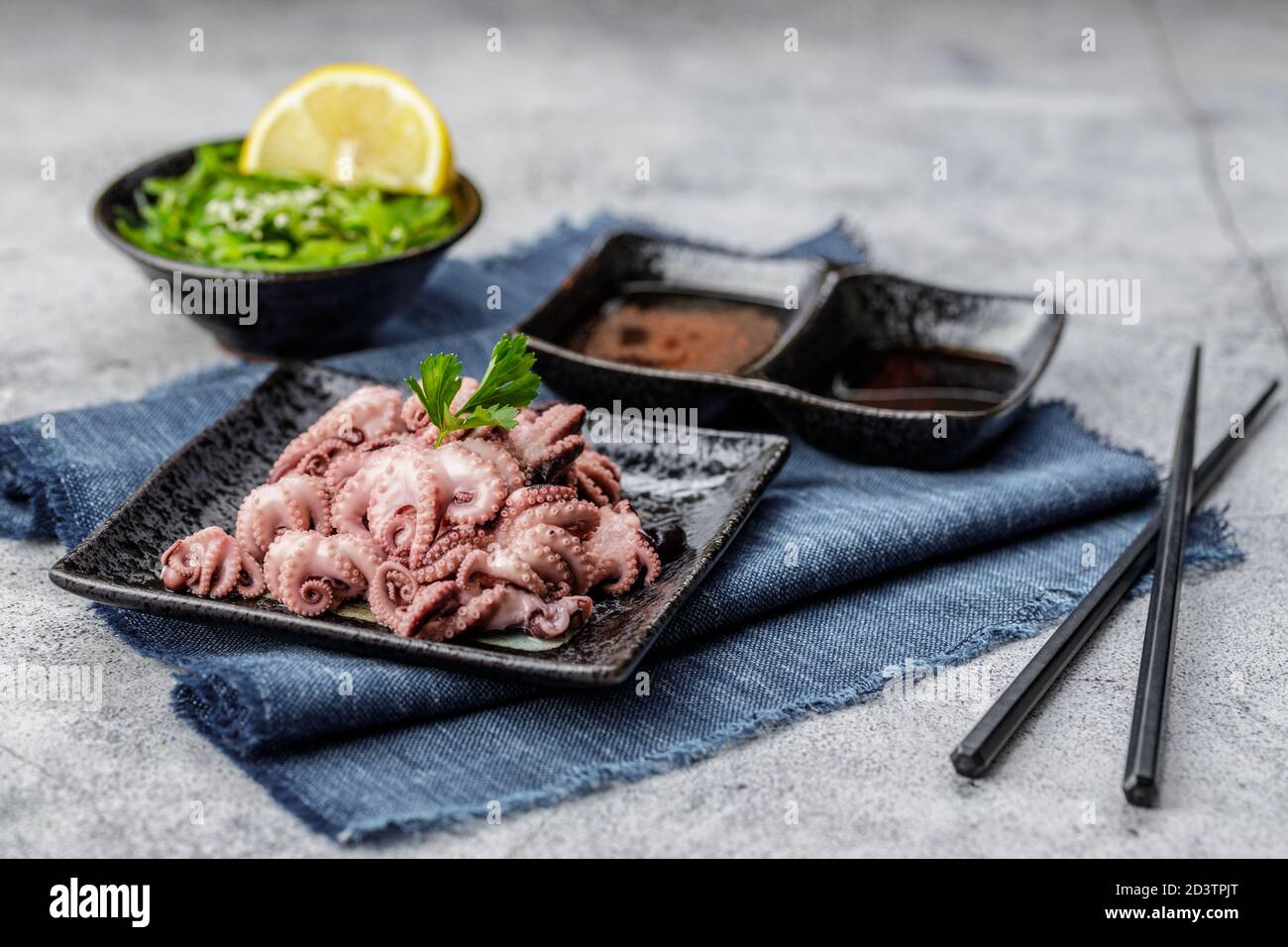 Tradizionale giapponese o concetto di pesce. Mini polpo bollito delizioso e sano e insalata di wakame o alghe con salsa di soia e limone serviti con Foto Stock