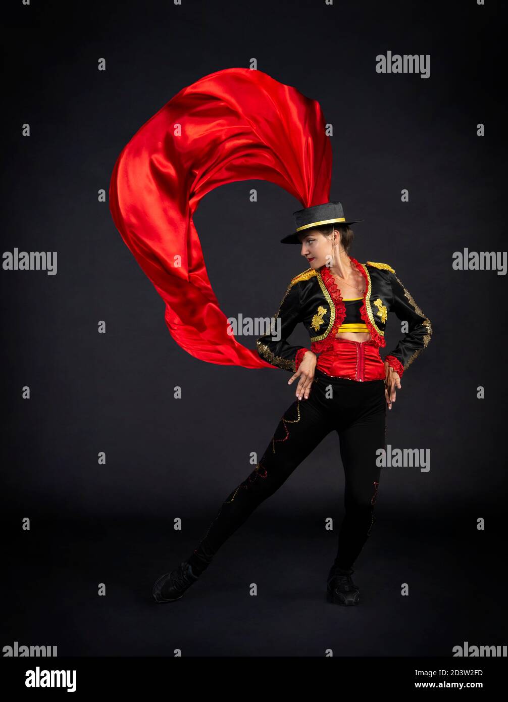 Donna di plastica che balla con grazia in un costume da palcoscenico stilizzato come un bullfighter. Riprese in studio su sfondo scuro. Foto Stock