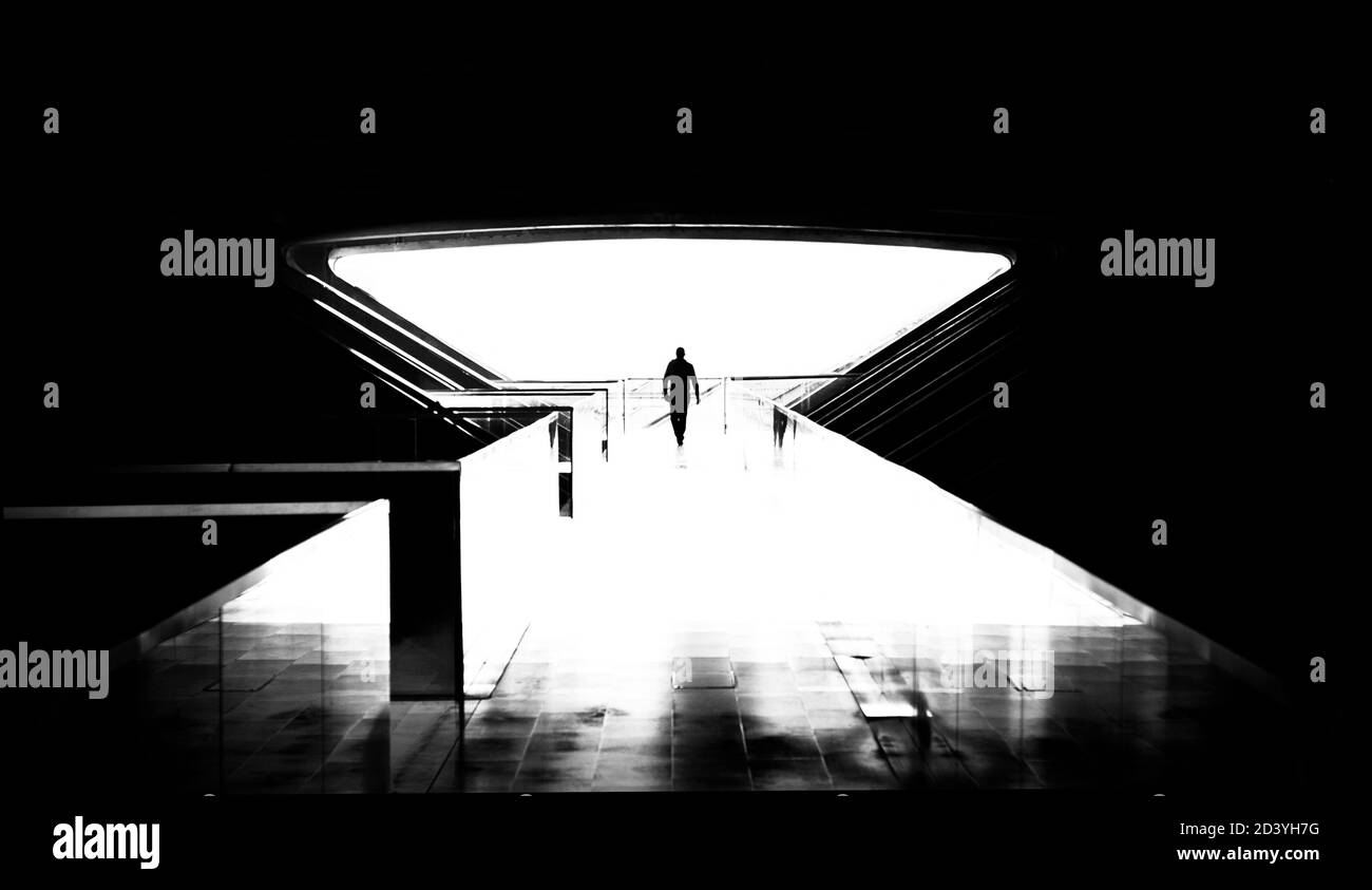Uomo che cammina verso la luce in Gare do Oriente a Lisbona, Portogallo, in un'immagine in bianco e nero ad alto contrasto. Concetto fantascientifico. Foto Stock