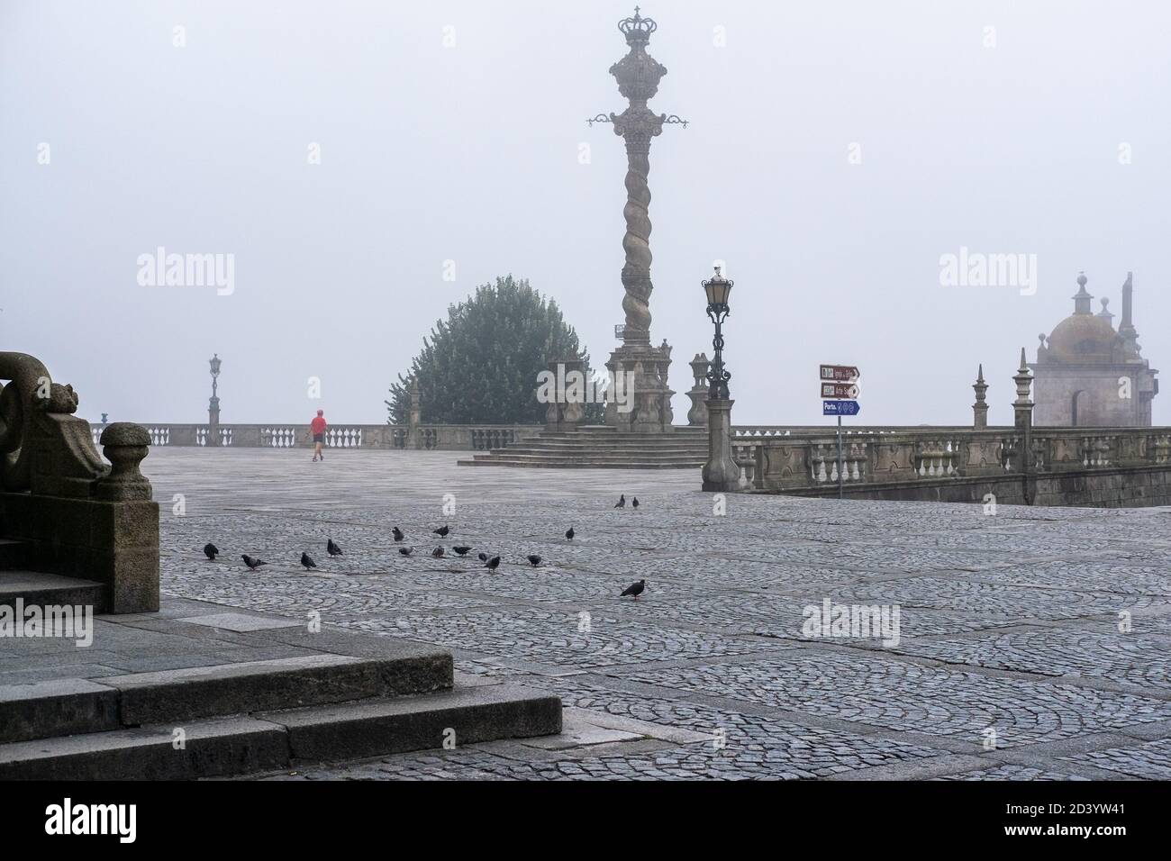 Uomo durante la passeggiata di mattina facendo sport a Terreiro da se A Porto con piccioni e senza persone Foto Stock