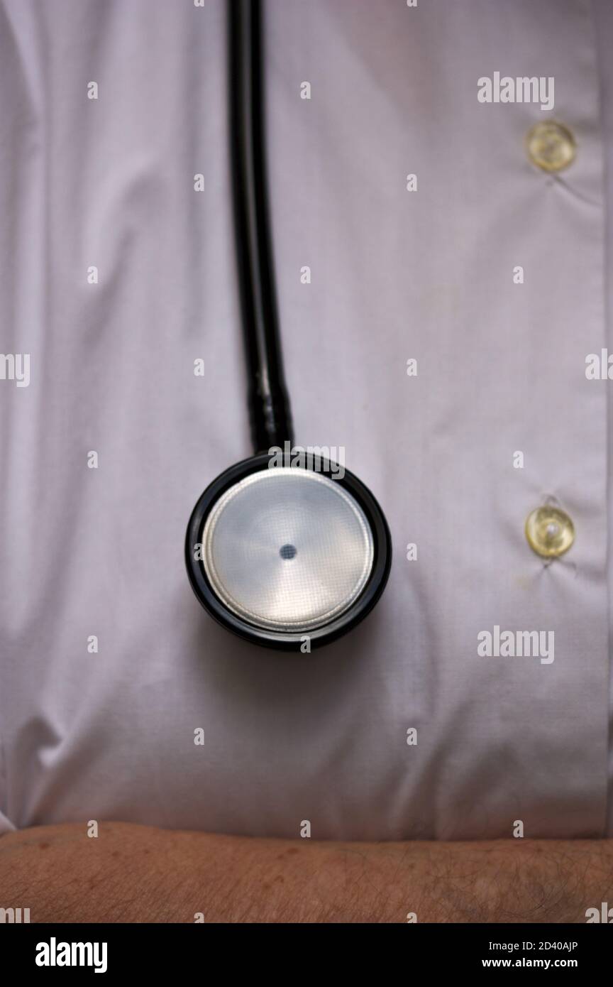 Primo piano di uno stetoscopio appeso su un pulsante bianco camicia che fa parte dell'uniforme di un medico Foto Stock
