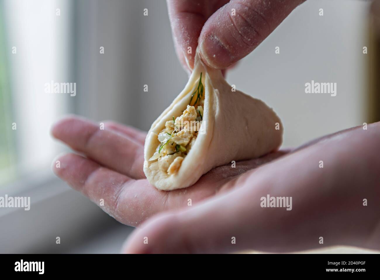 Una delle fasi di produzione di gnocchi di carne - sopra la tavola su un pezzo di impasto è una carne ripieno di verde accanto ad un cumulo di farina Foto Stock