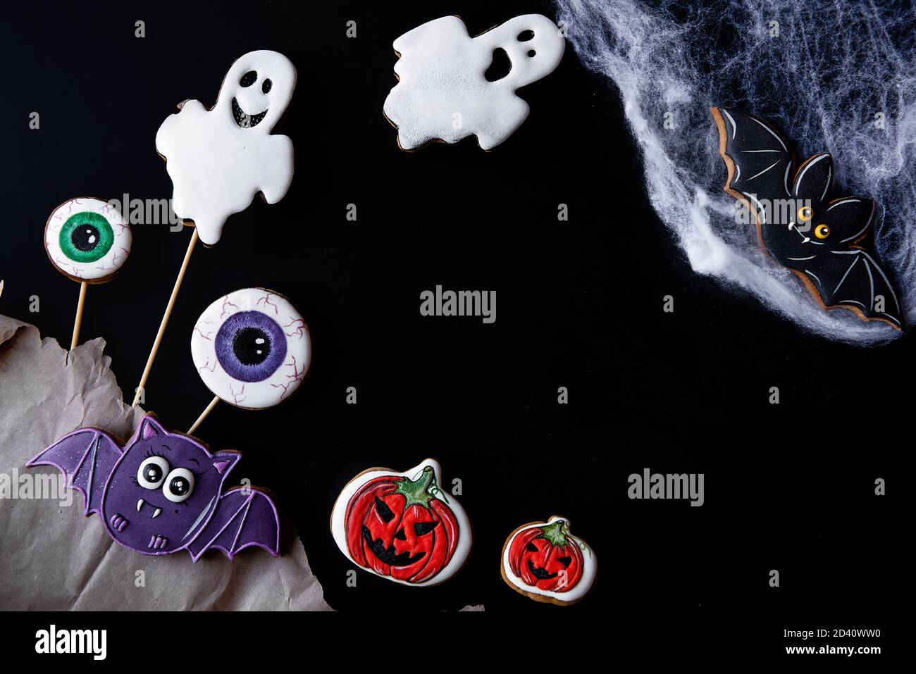 Flatlay di pan di zenzero dipinto per Halloween. Cibo per bambini. Decorazioni per il tavolo festivo: Fantasmi, pipistrelli, occhi spaventosi, ciottoli, zucche. Copia Foto Stock