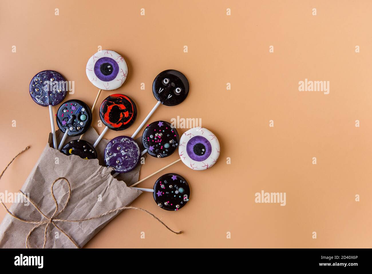 Bouquet creativo di fiori da lecca lollipop occhio su un bastone come regalo per Halloween. Isolato su uno sfondo arancione in imballaggio artigianale, scheda Foto Stock