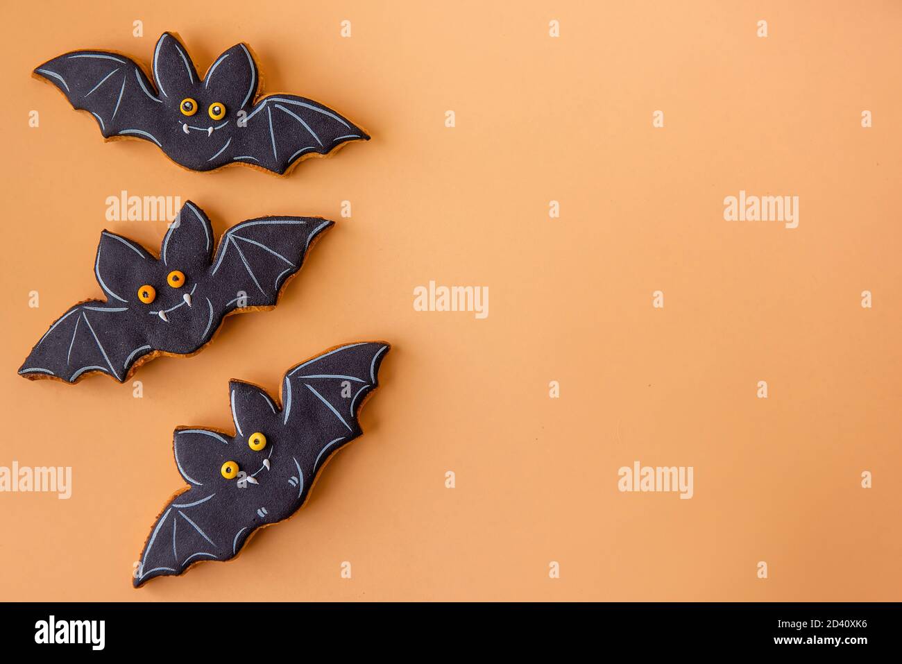 Modello di Halloween per cartolina. I pipistrelli neri allegri sono isolati su uno sfondo arancione. Congratulazioni per la vacanza. Cibo per bambini, spazio fotocopie Foto Stock