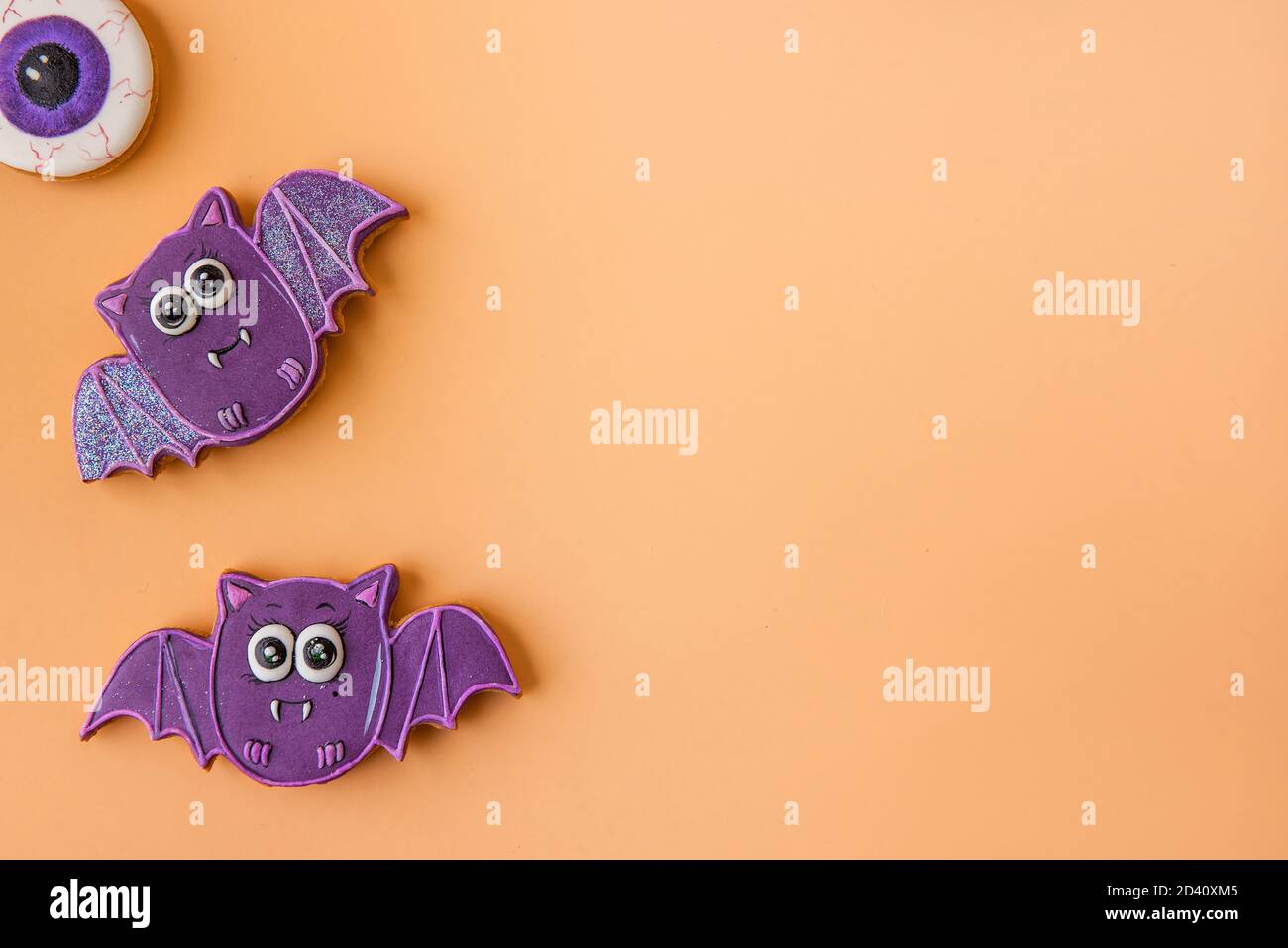 Modello di Halloween per cartolina. I pipistrelli viola allegri sono isolati su uno sfondo arancione. Congratulazioni per la vacanza. Cibo per bambini, spazio fotocopie Foto Stock