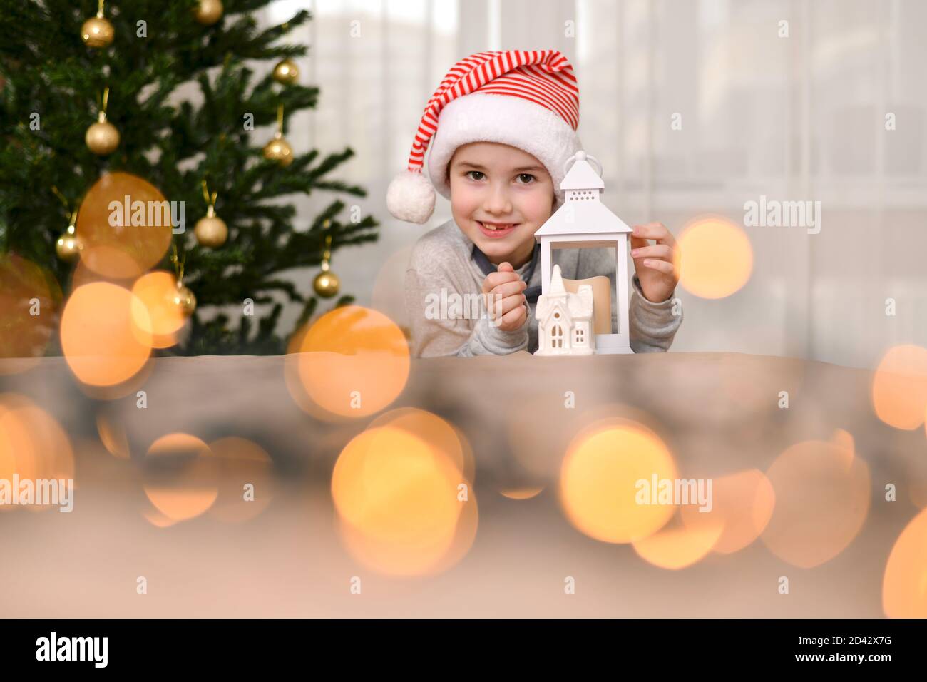 Un bambino nel cappellino di Capodanno, giace sul palmo in un abbraccio con una lampada e sorride ampiamente labbra. Foto Stock