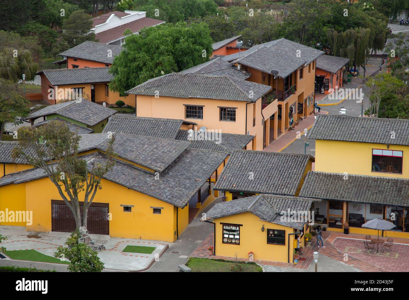 villaggio con diverse piccole case gialle e rosa con tetto di tegole nere, alberi tra le case Foto Stock
