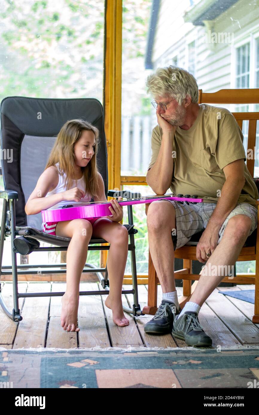 la ragazza giovane mostra il nonno che cosa sta imparando su lei nuova chitarra Foto Stock