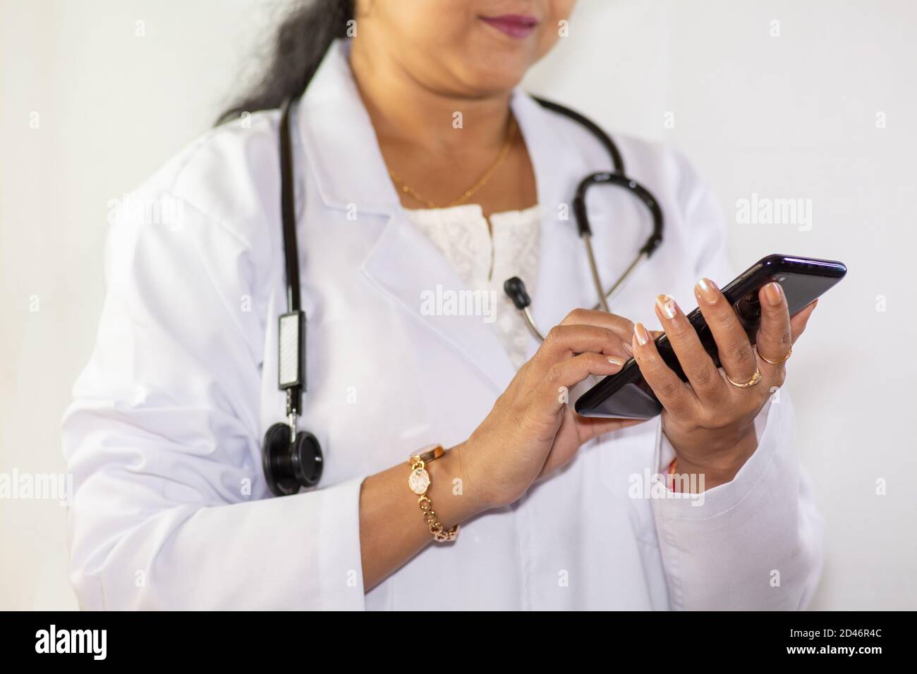 Medico indiano controlla sul suo telefono cellulare ad un medico Clinica a Kolkata Foto Stock