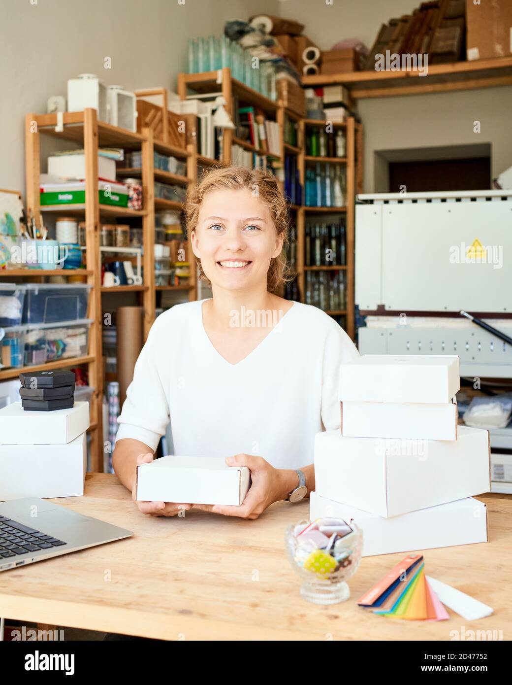 Felice proprietario di affari locali. Donna imprenditore che raccoglie e impacchettano regali Foto Stock