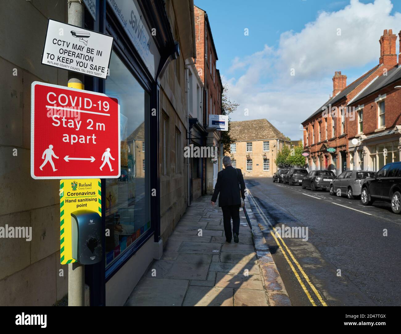 Avviso "a distanza di 2 m" sopra un punto di sanificazione delle mani e sotto un avviso tvcc su una strada a Oakham, Rutland, Inghilterra, durante l'epidemia di coronavirus, Foto Stock