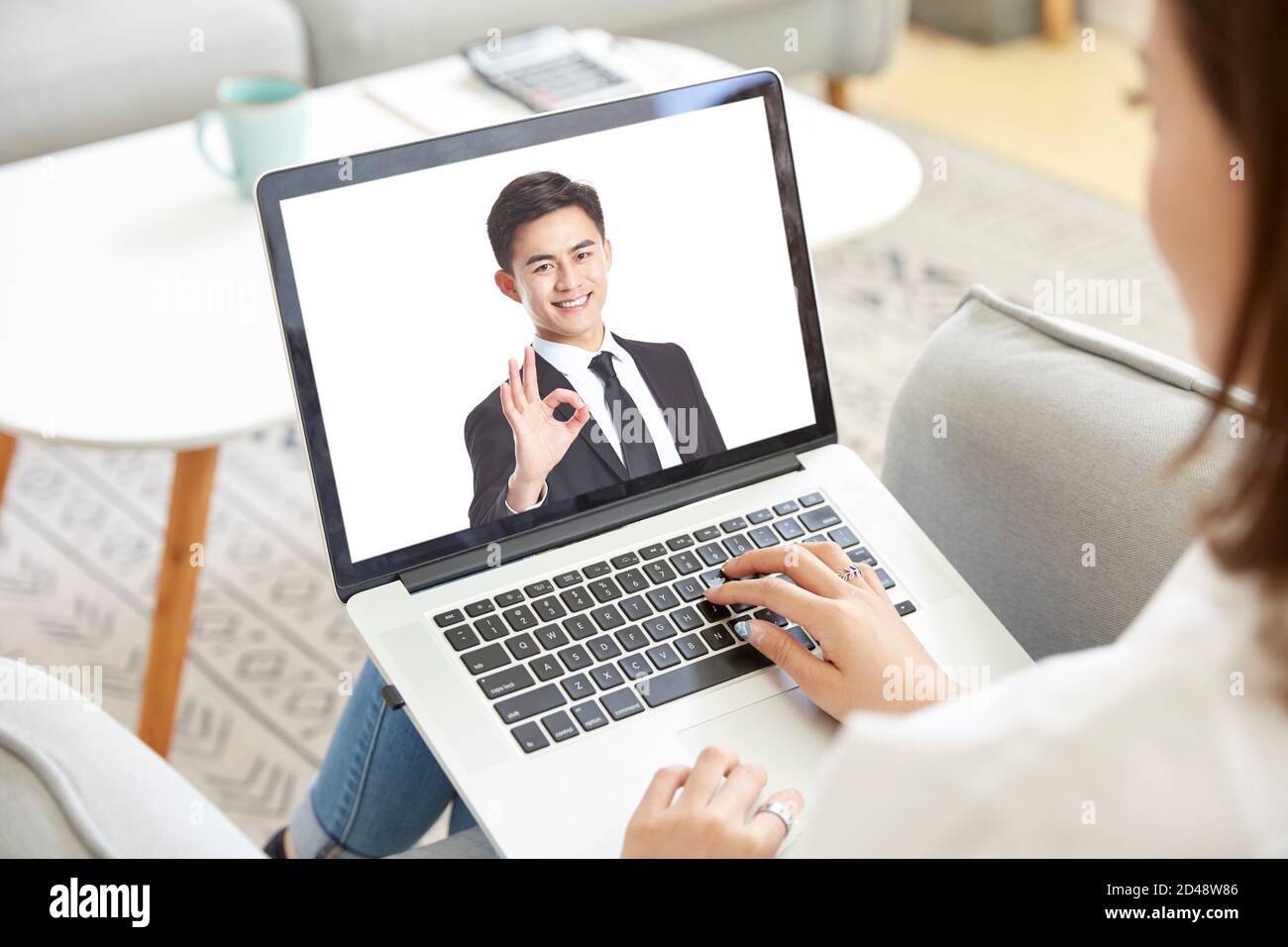 giovane donna asiatica d'affari che lavora da casa incontro con la collega online tramite chat video utilizzando un computer portatile Foto Stock