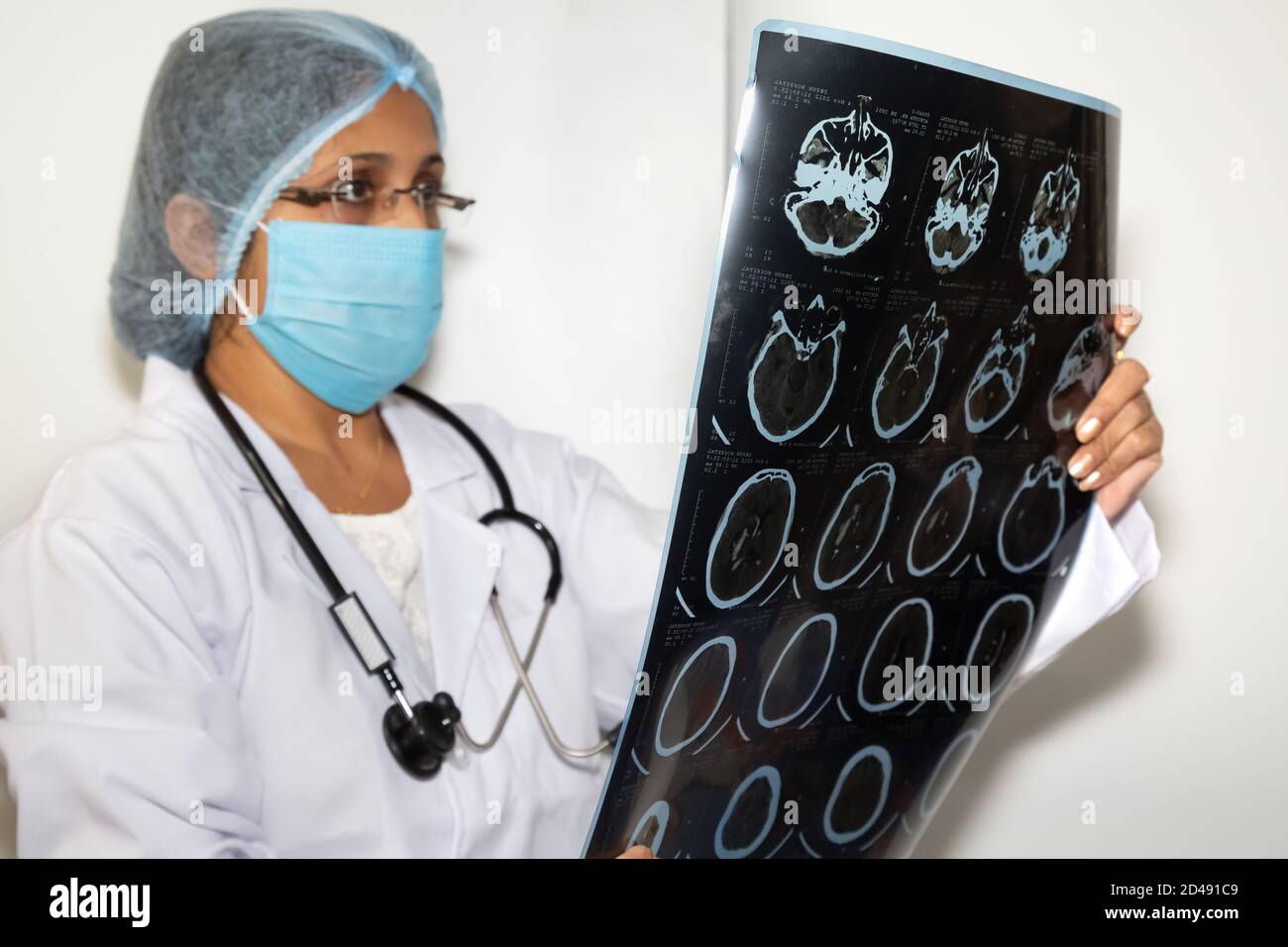 Neurologo femminile indiano esamina una piastra di scansione TC cerebrale a. una clinica sanitaria Foto Stock
