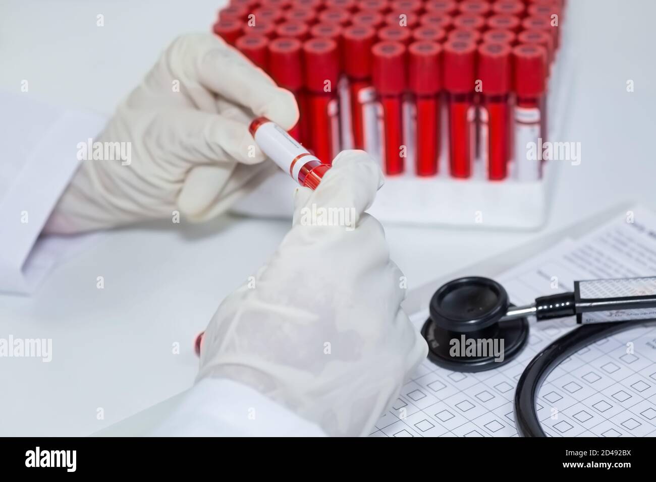 Il medico indiano esamina le fiale dei campioni di analisi del sangue dei pazienti durante la preparazione rapporto medico Foto Stock