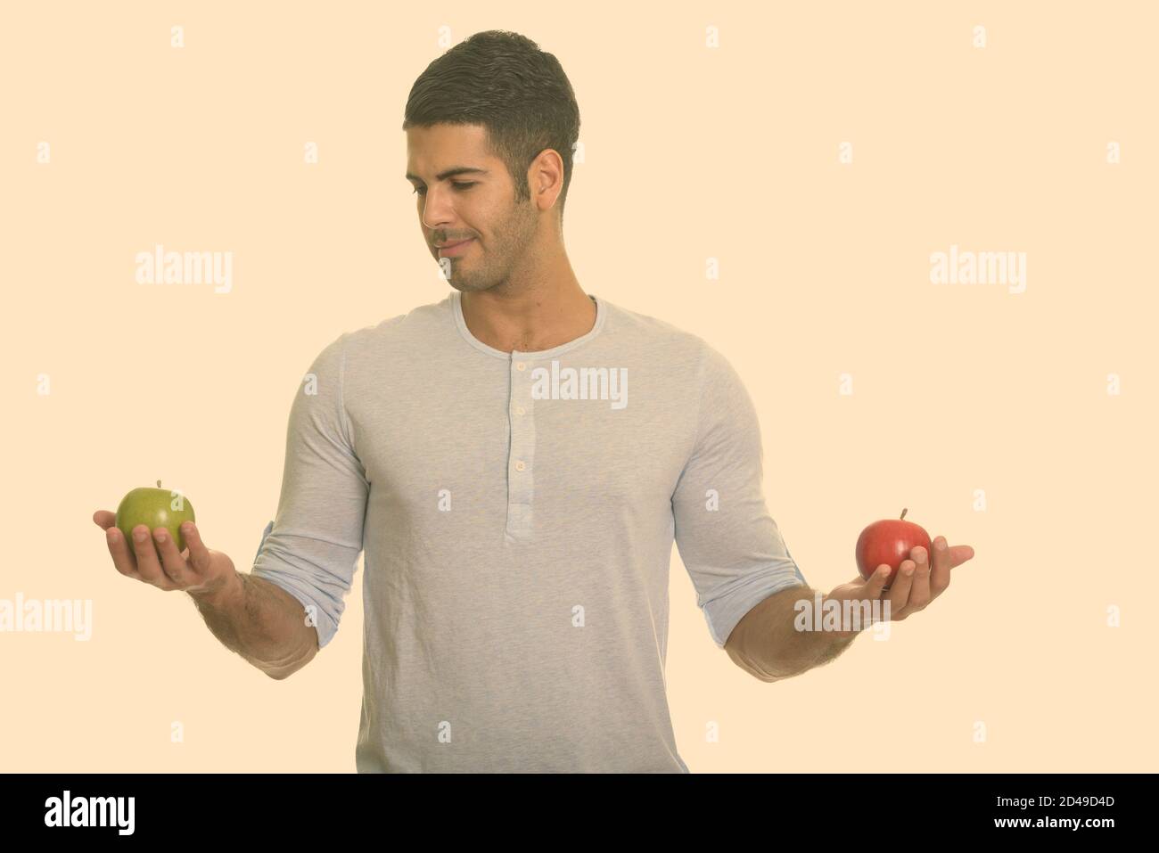 Bel giovane uomo persiano scegliendo tra rosso e verde mela Foto Stock