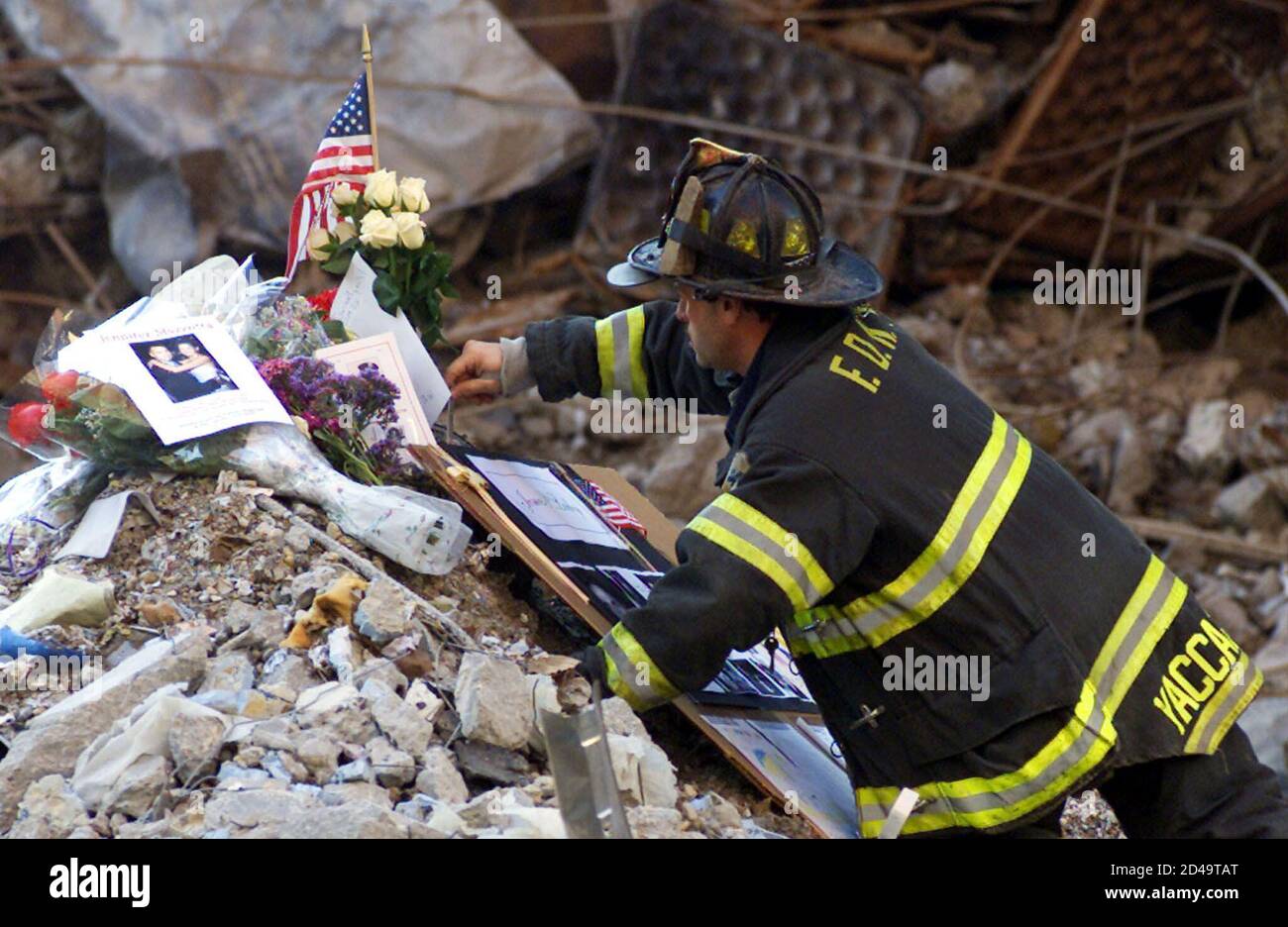Un vigile del fuoco di New York City colloca fiori e ricordi dei membri della famiglia delle vittime del disastro del World Trade Center nel relitto a seguito di un servizio commemorativo per le vittime dell'attacco del 11 settembre presso il sito di New York, il 28 ottobre 2001. REUTERS/Mike Segar MS Foto Stock