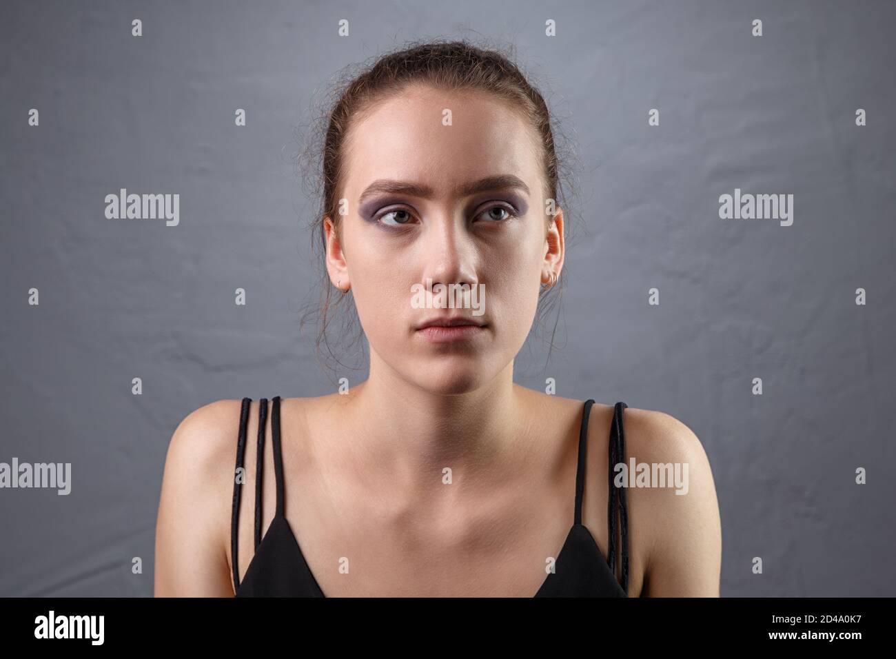 Foto di giovane donna con trucco incompiuto guardando in su Foto Stock