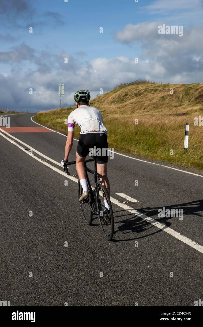Ciclista visto da dietro a una salita impegnativa Della sella su una strada Yorkshire Moors in anticipo Autunno Foto Stock