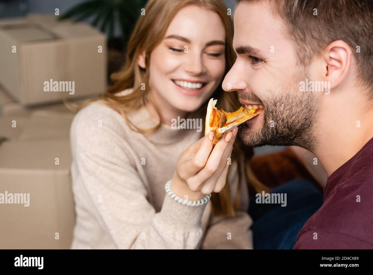 fuoco selettivo della donna che alimenta l'uomo bearded con la pizza Foto Stock
