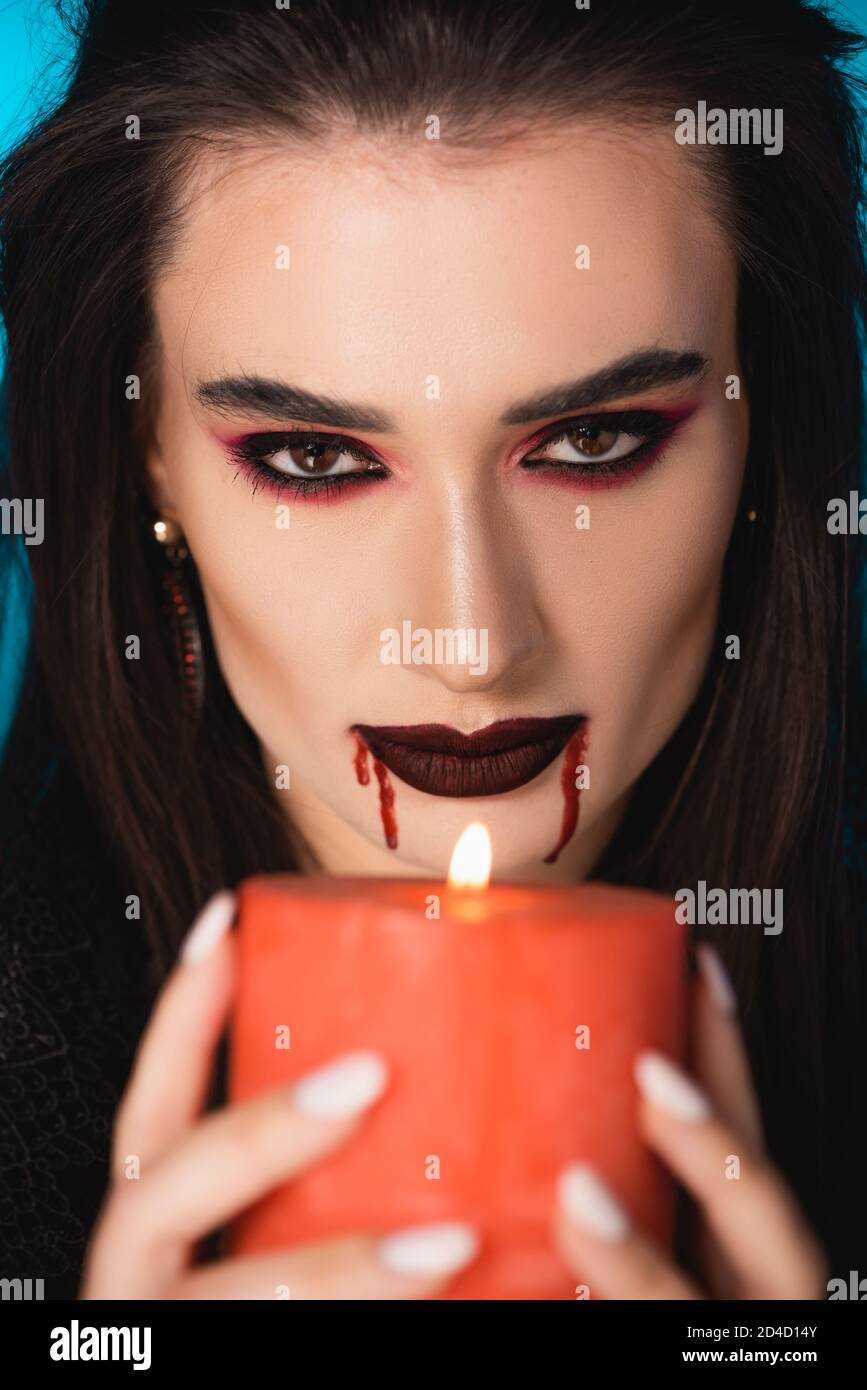 fuoco selettivo della donna con il sangue sulla faccia che tiene bruciare candela Foto Stock
