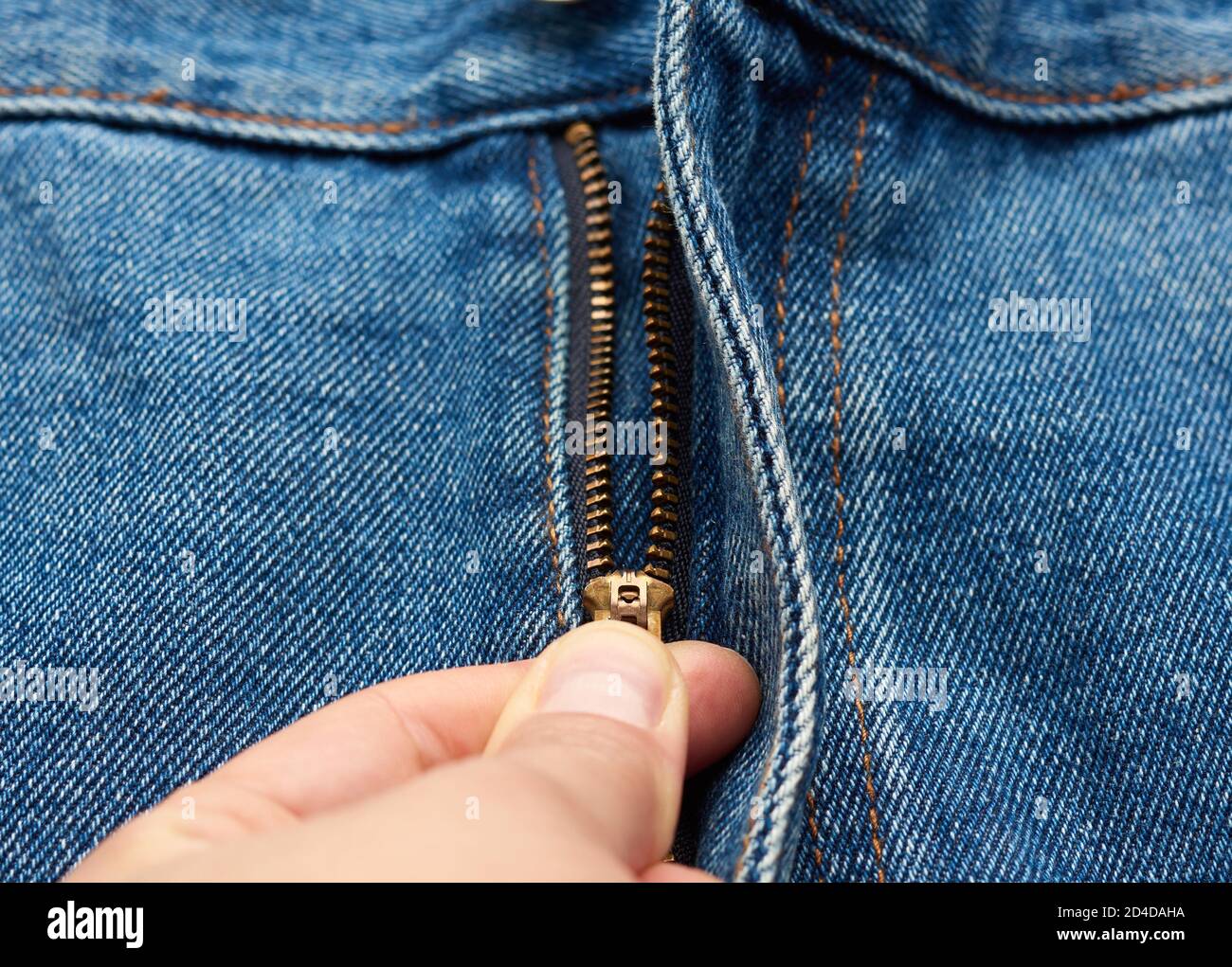 la mano scomprime la cerniera in ferro sulla mosca dei pantaloni jeans blu, fuoco selettivo Foto Stock