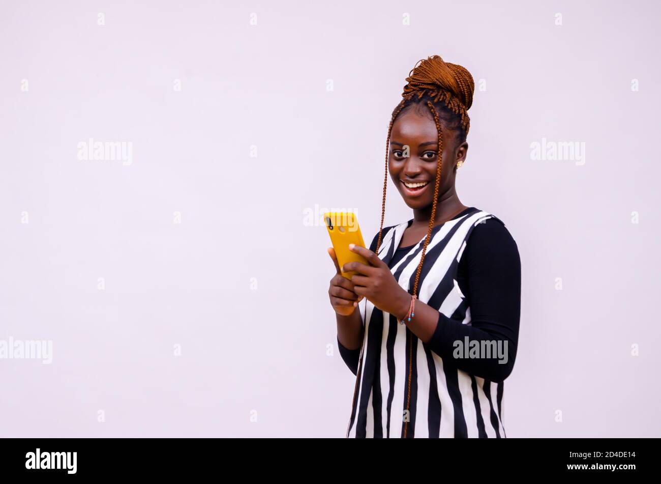 nero africano giovane hipster sorridente utilizzando il telefono cellulare, la lettura di testo, la navigazione in internet, la visione di video online Foto Stock