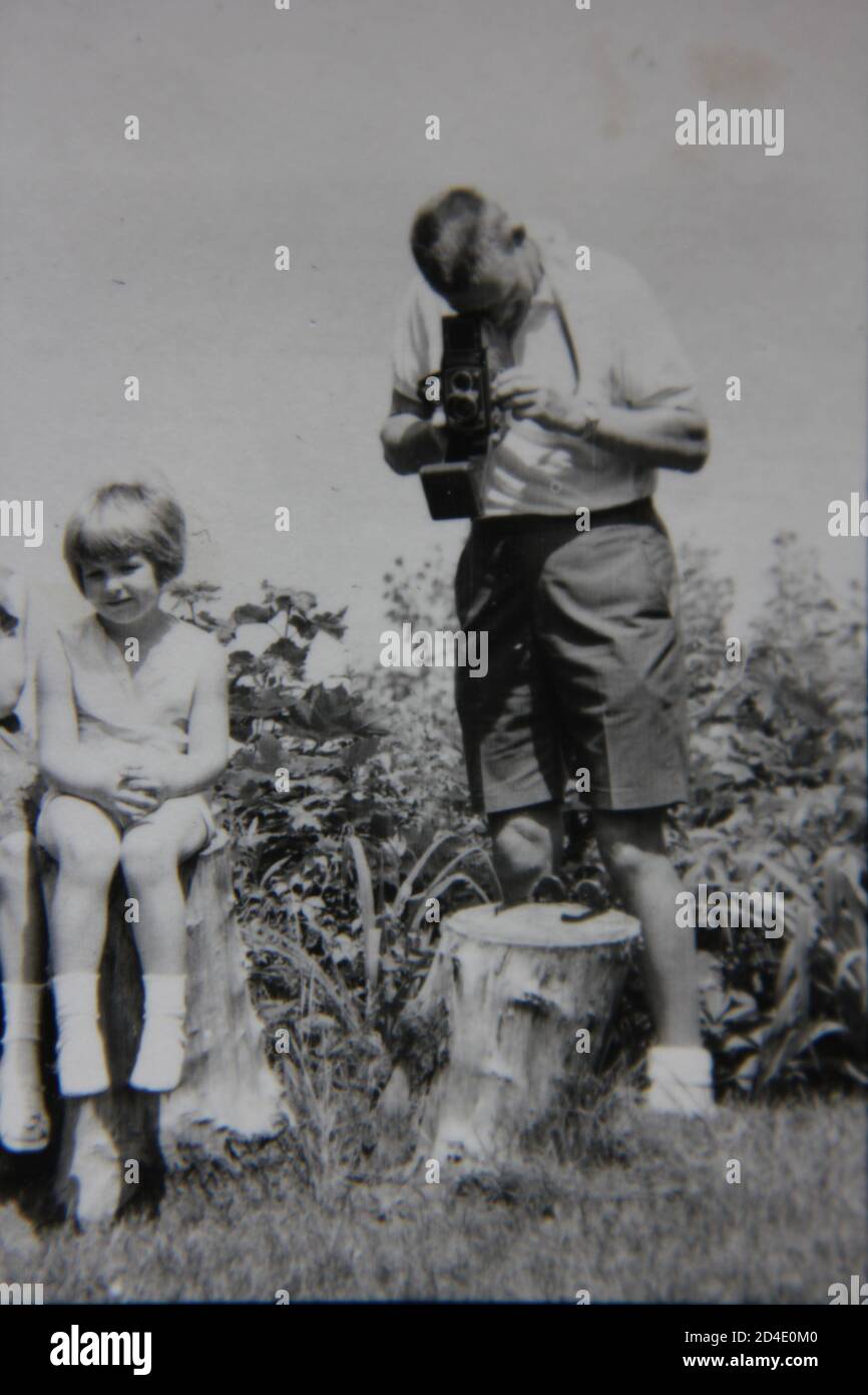Fine 1970 vintage fotografia in bianco e nero di un hobbista shutterbug che prende la macchina fotografica fuori per una coppia di immagini. Foto Stock